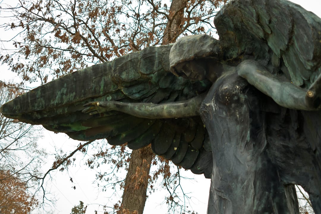 The bronze Black Angel monument towering over headstones at Oakland Cemetery in Iowa City, Iowa