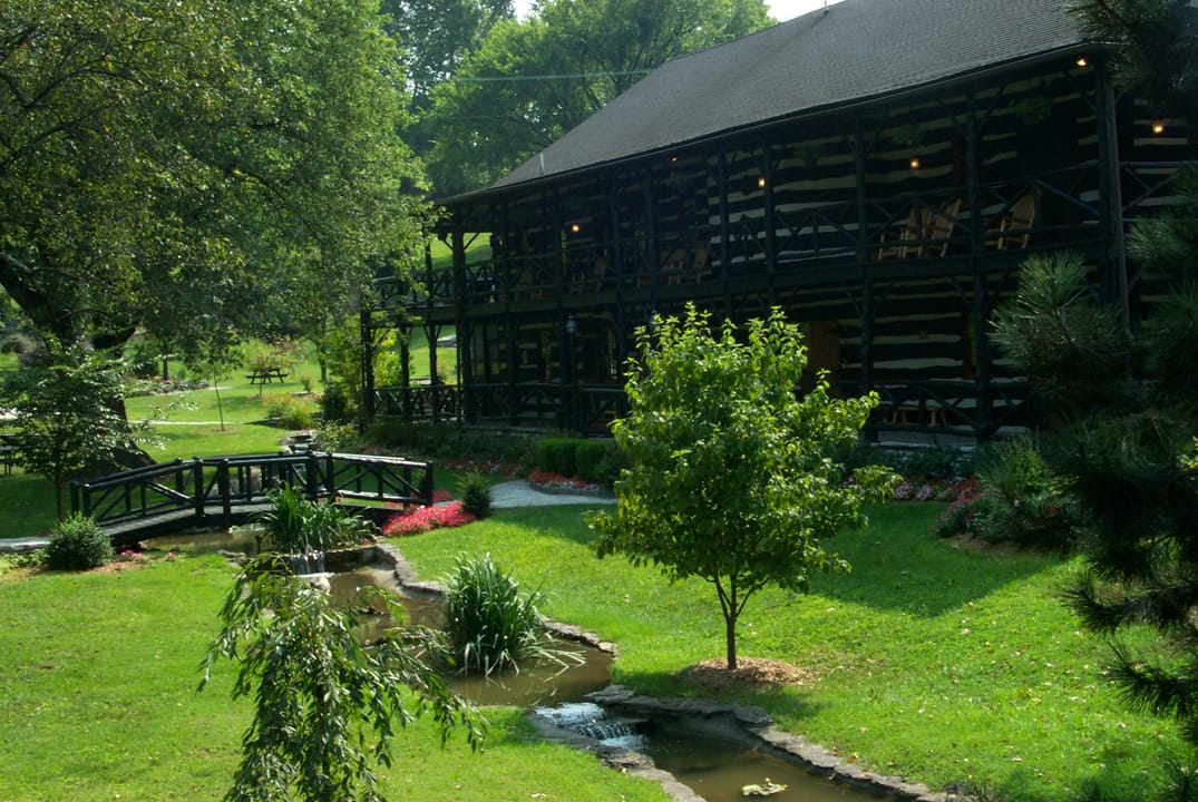 The landscaped grounds and log guest house at Buffalo Trace Distillery, with a footbridge over a small stream, Frankfort, Kentucky.