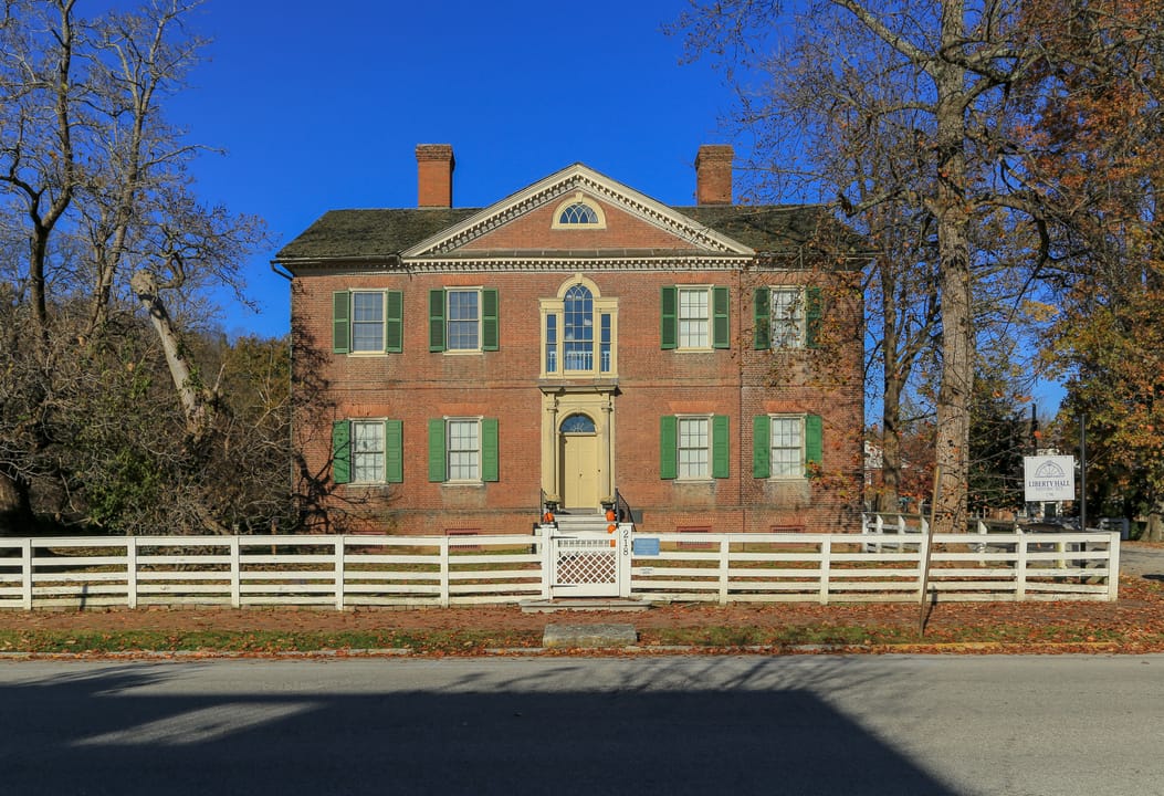 Front facade of Liberty Hall under a clear blue winter sky, seen from the street beyond the picket fence, November 2018.
