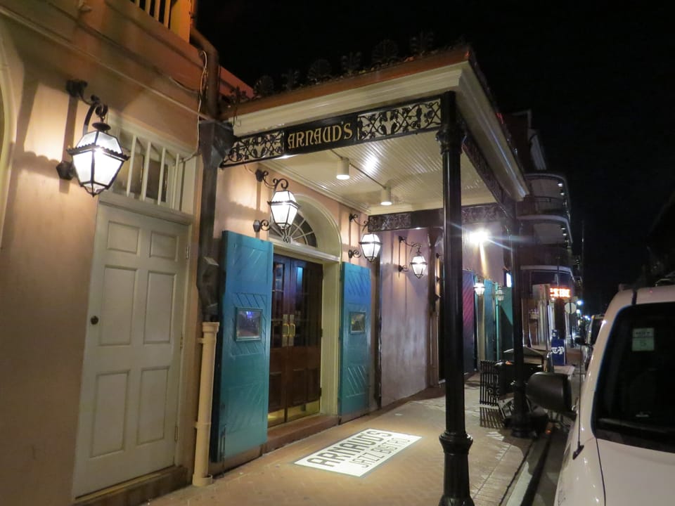 Daytime exterior of Arnaud's Restaurant on Bienville Street in the French Quarter, showing the galleried facade and entrance flags.