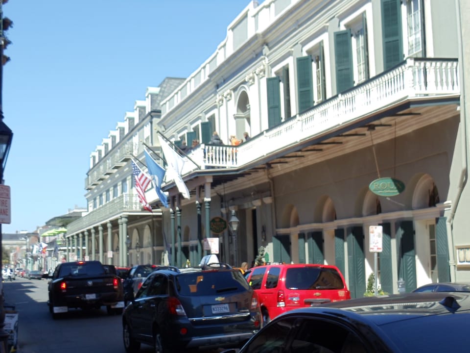 Street-level view of the Bourbon Orleans Hotel's balconied facade and flags on Orleans Street, with parked cars in the foreground, 2013.