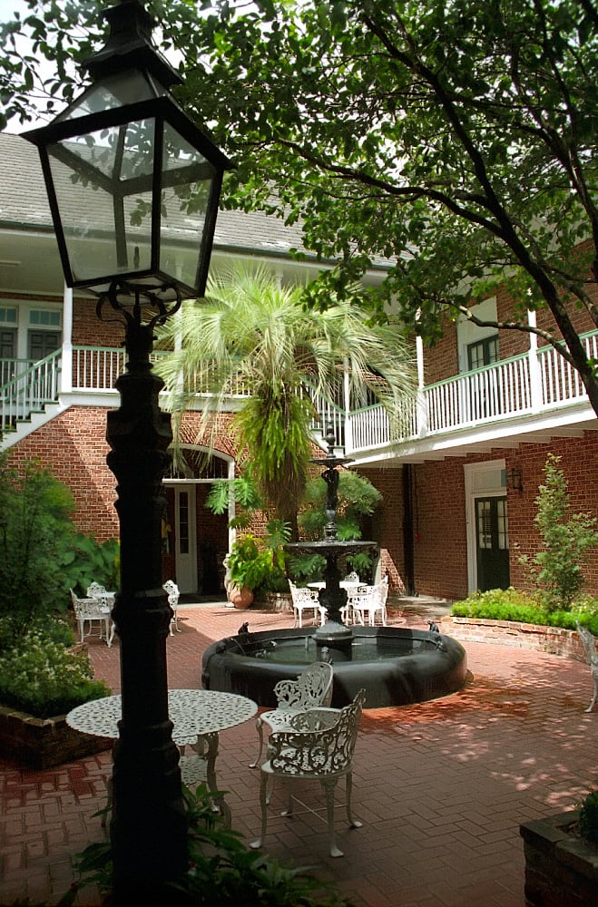 Tropical interior courtyard with fountain at Hotel Provincial in the French Quarter of New Orleans, surrounded by historic Creole architecture.
