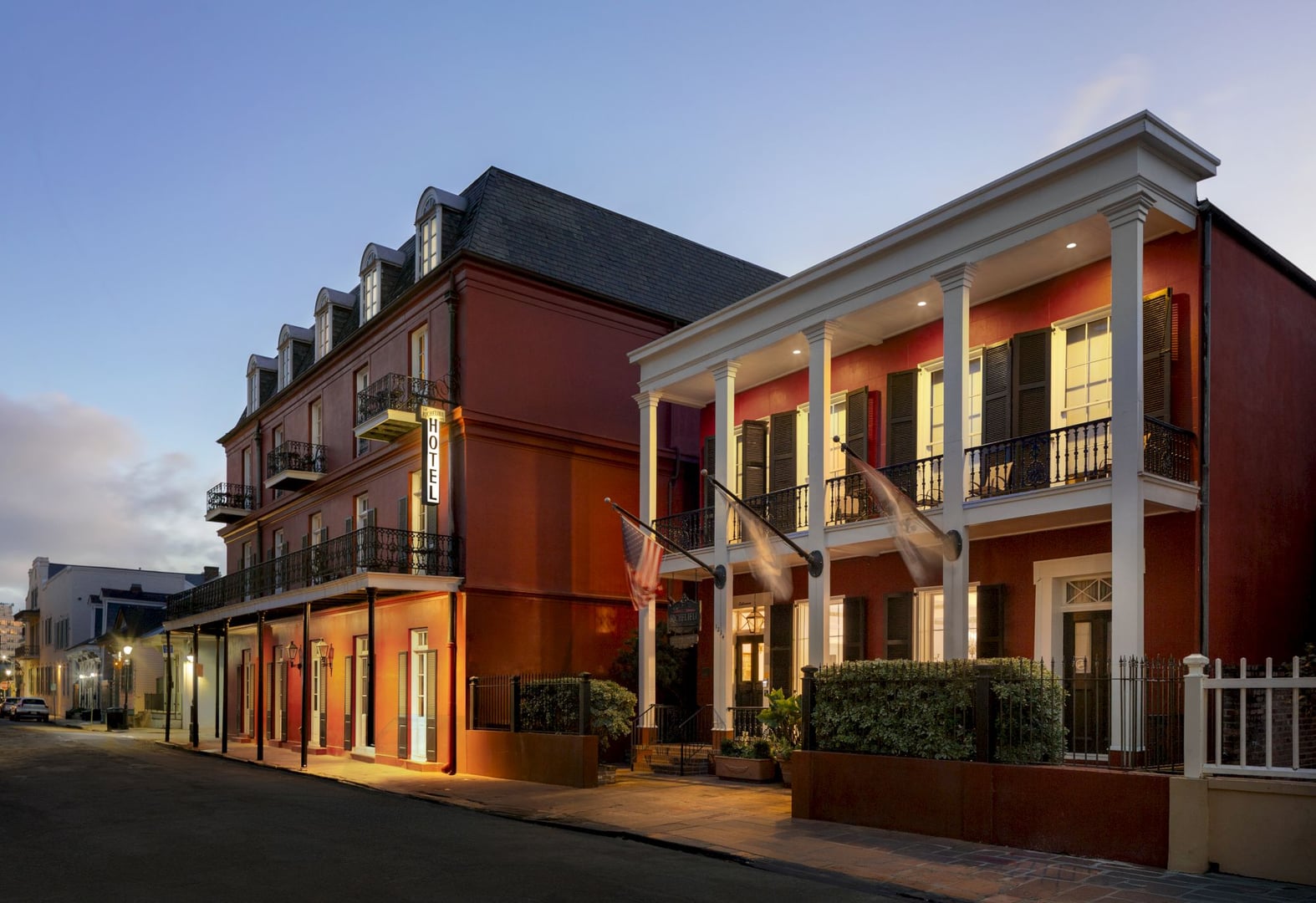 Exterior of Hotel Le Richelieu, a 1845 boutique hotel with red brick facade and wrought iron balconies on Chartres Street in the New Orleans French Quarter.