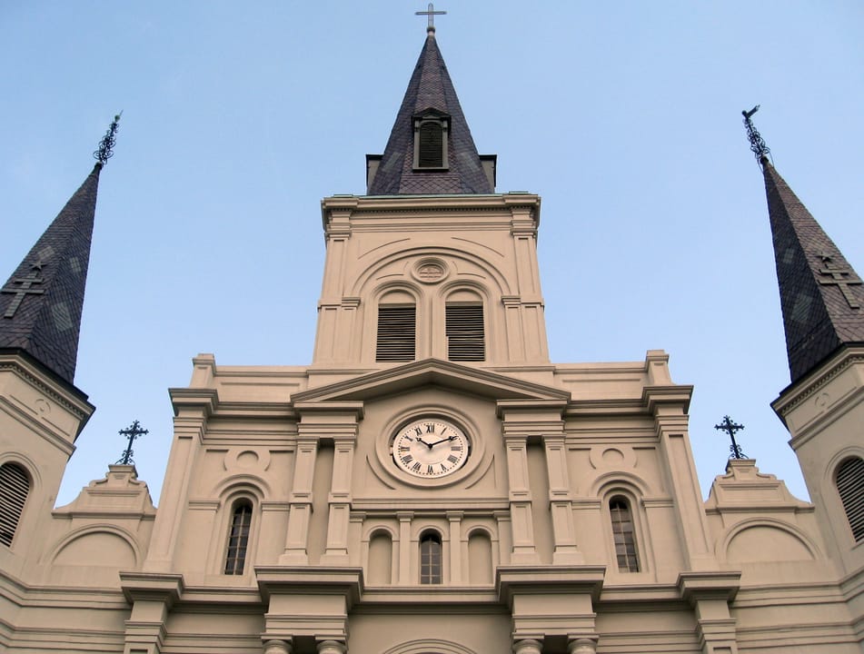 Close-up of St. Louis Cathedral's central spire and clock face against a clear sky, New Orleans.