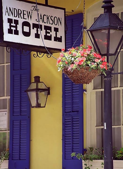 The hanging "The Andrew Jackson Hotel" sign beside a flower basket and gas lamp at the hotel's entrance, New Orleans