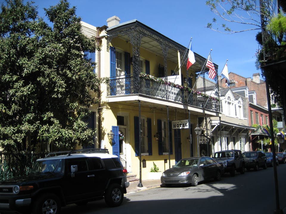 The Andrew Jackson Hotel's yellow two-storey facade with its iron-lace balcony, three flags and hanging sign on Royal Street in the French Quarter, New Orleans, early 2007.