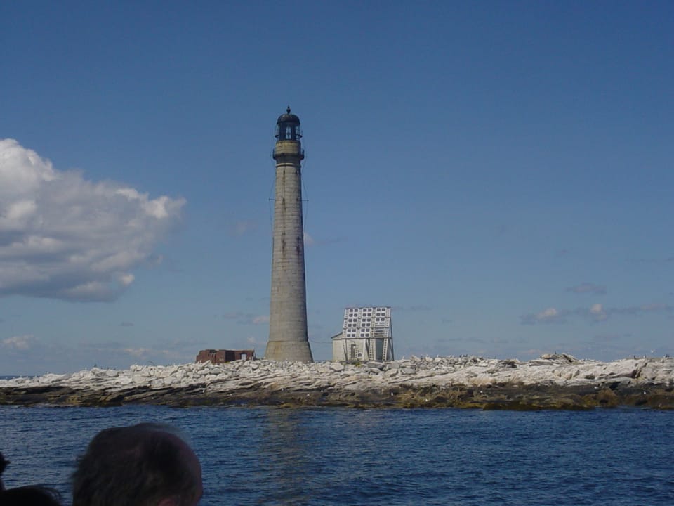 Boon Island Light and its rubble-stone outbuildings on the bare granite island, seen from the water on a clear day