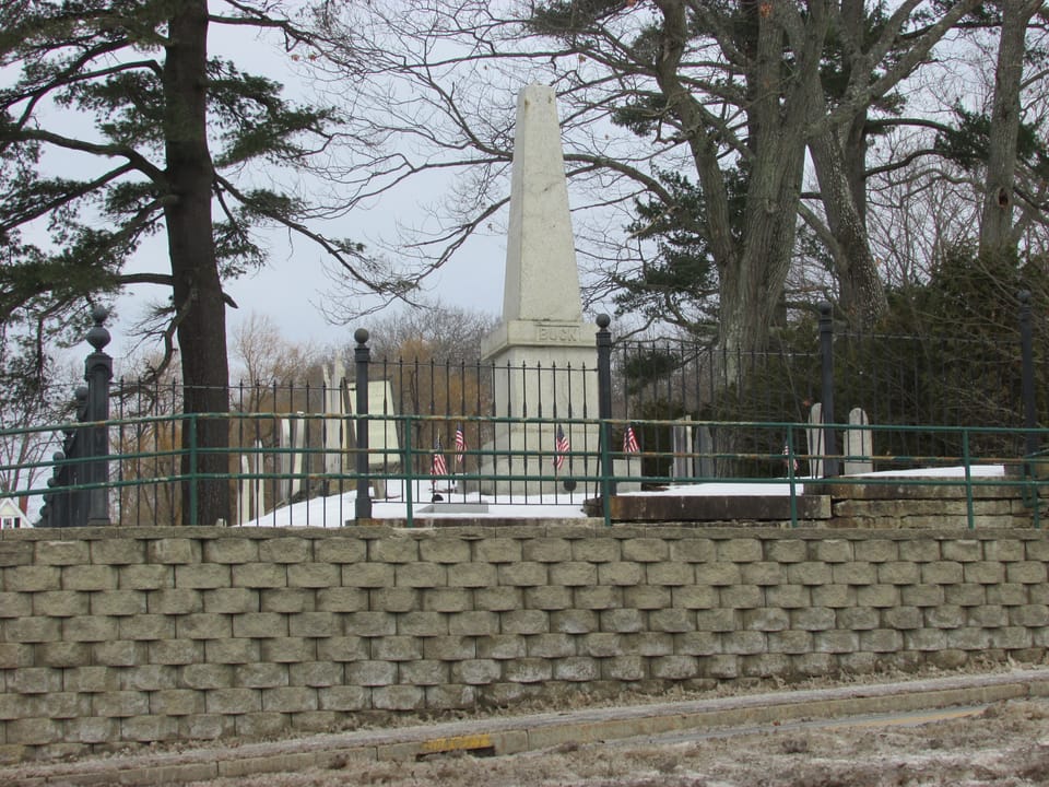 The granite Buck Monument to Colonel Jonathan Buck, inscribed BUCK, inside its iron-fenced plot in Buck Cemetery, Bucksport, Maine.