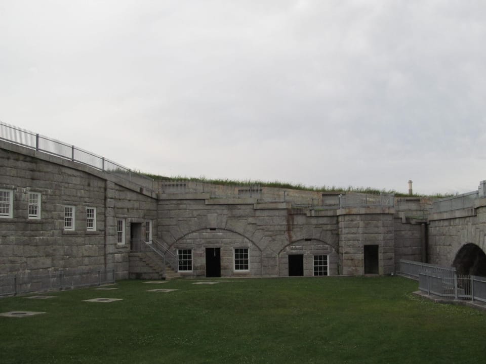 Interior parade-ground courtyard at Fort Knox, Prospect, Maine, showing the arched granite casemate arcade and grass courtyard; public visitor area, no people.
