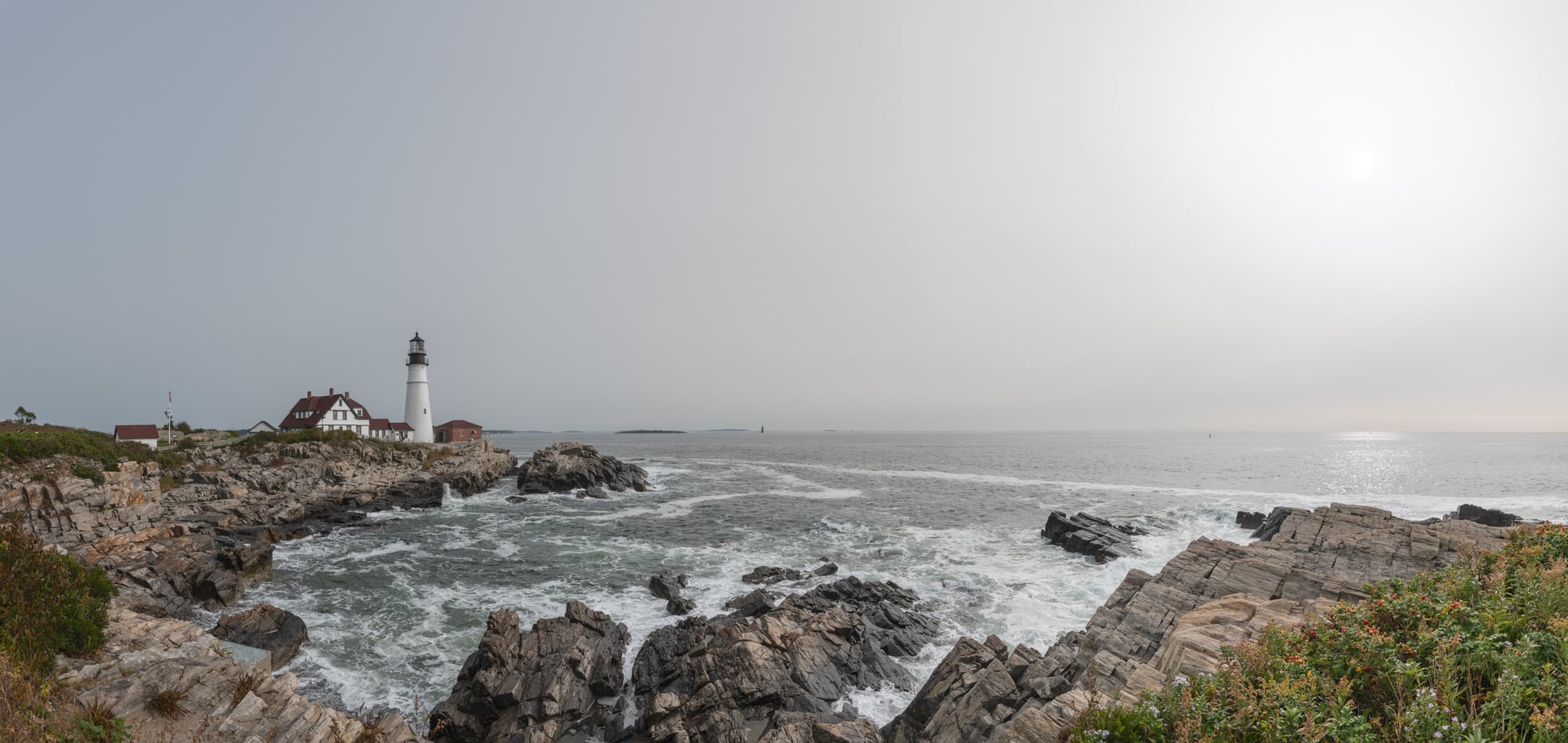 Portland Head Light, the 1791 white-stone lighthouse with red-roofed keeper's quarters, on the rocky Casco Bay coast at Cape Elizabeth, Maine