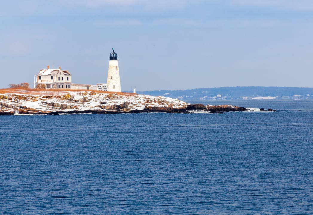 The 47-foot granite tower and keeper's house of Wood Island Light, Biddeford Pool, Maine, seen from the island's rocky shore, May 2017.