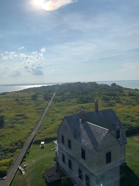 Elevated view from the top of the tower looking down over the keeper's house and the boardwalk that is the island's only access route, October 2021.
