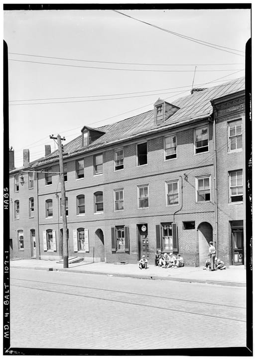 Brick row at 1626-1628 Thames Street in Fells Point, Baltimore, with arched street-level passages and dormers in its metal roof, photographed in the 1930s for the Historic American Buildings Survey. The Horse You Came In On Saloon is at 1626 Thames S