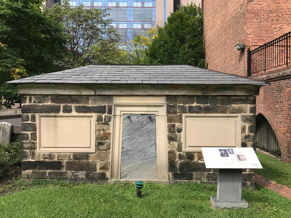One of the stone burial vaults built into the Westminster Burying Ground's catacombs, with its inscribed plaques, beside the Westminster Hall building