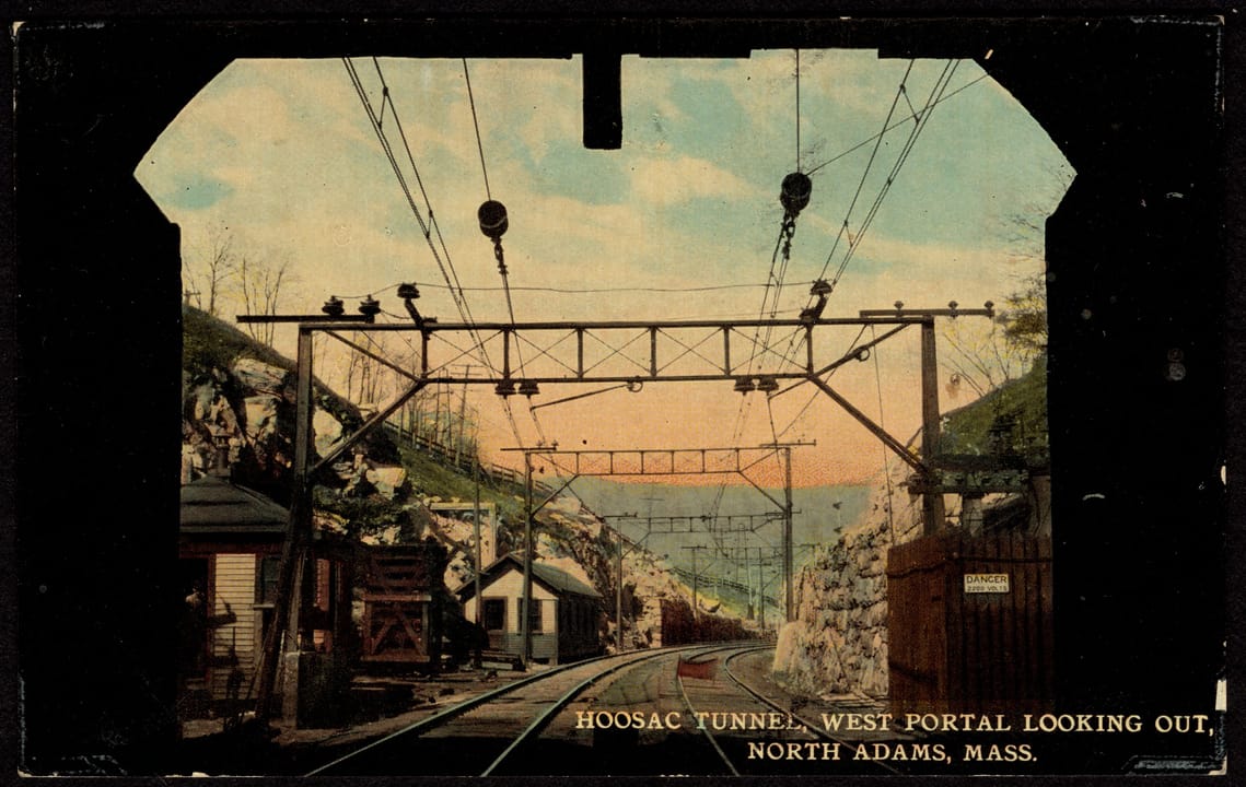 Looking out through the west portal of the Hoosac Tunnel toward North Adams, with the overhead electric wires installed after 1911; early 20th-century postcard view.