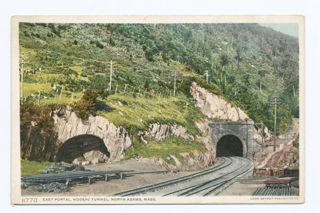 The masonry east portal of the Hoosac Tunnel beside the arch of the earlier abandoned bore, on a Detroit Publishing Company photochrom postcard, about 1908.