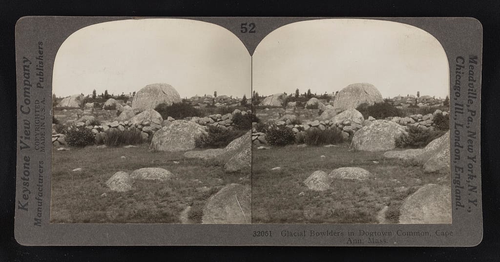 A 1928 Keystone View Company stereograph card titled 'Glacial Bowlders in Dogtown Common, Cape Ann, Mass.,' showing the boulder field as it appeared nearly a century ago.