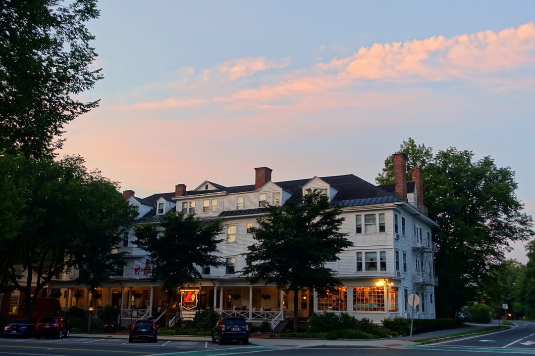 The Red Lion Inn seen across Main Street at dusk, with its porch lit under a pink evening sky, Stockbridge, Massachusetts.