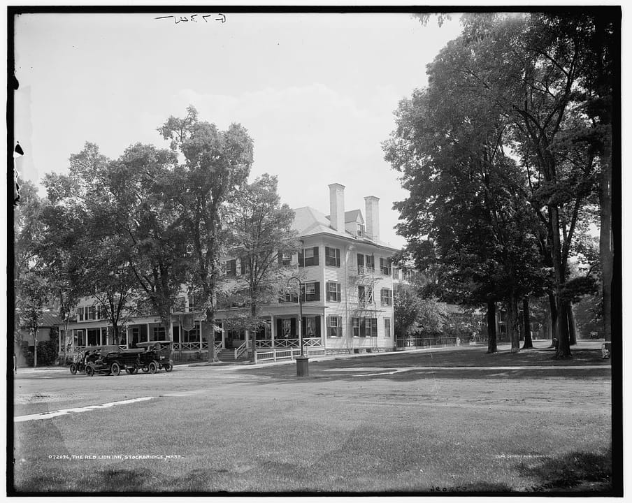 The Red Lion Inn seen across a lawn through shade trees on Main Street, with an early automobile at the roadside, from a Detroit Publishing Company negative of about 1905-15.
