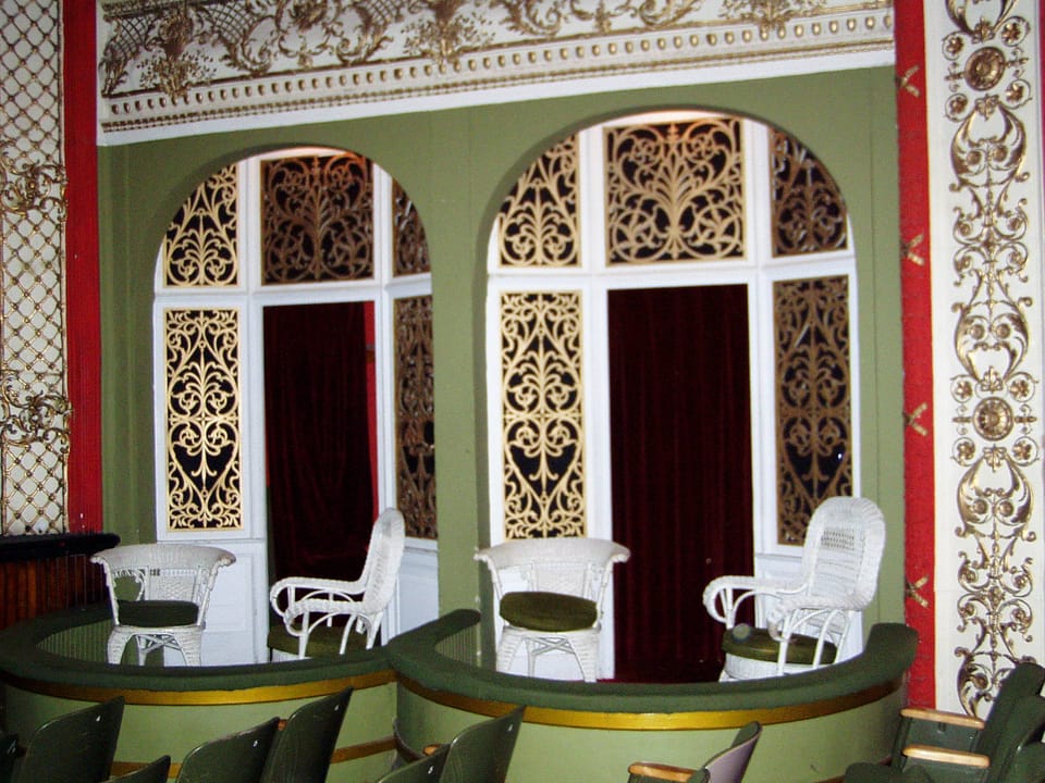 Two box seats with white wicker chairs, gilded fretwork screens and red velvet curtains inside the Calumet Theatre auditorium, Calumet, Michigan (2004).