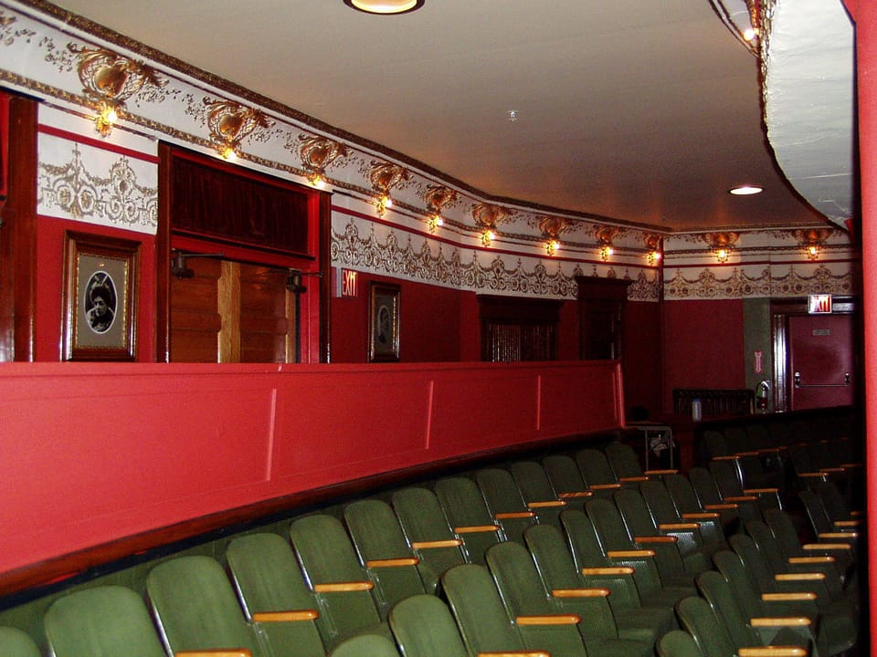 Side wall of the Calumet Theatre auditorium with its gilded frieze, red balcony front and rows of green seats, Calumet, Michigan (2004).