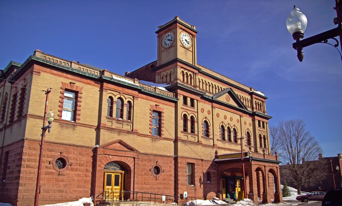 The Calumet Theatre's clock tower, buff brick walls, red sandstone base and arched entrance seen from the street corner in winter, Calumet, Michigan (March 2005).