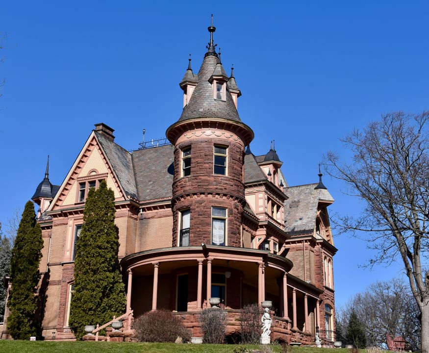 Closer summer exterior view of Henderson Castle from the front lawn, showing the full turret, gables and porch.