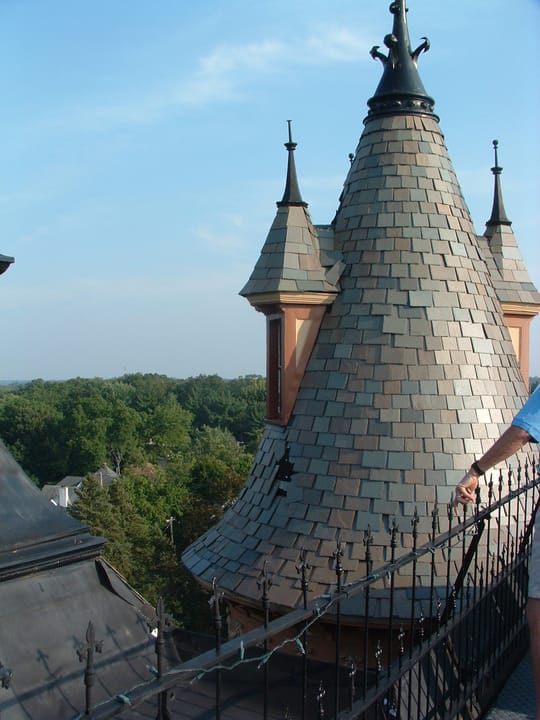 Close daytime view of Henderson Castle's distinctive conical corner turret and widow's-walk railing.