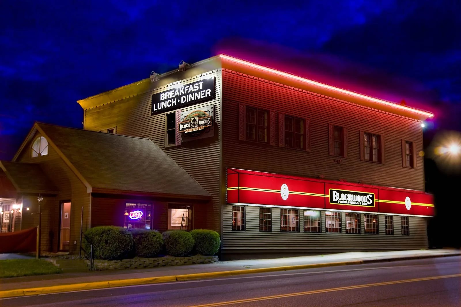 Black Woods Bar and Grill exterior at night, showing the illuminated building facade with Blackwoods sign at 612 7th Avenue in Two Harbors, Minnesota