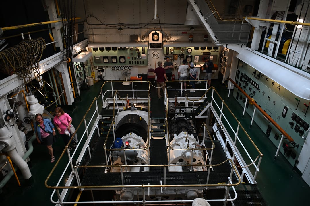 Interior view of the SS William A. Irvin's preserved engine room, part of the public museum-ship tour, with visitors viewing the machinery below.
