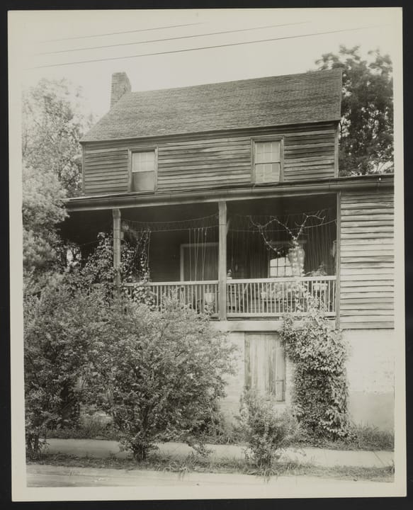 1938 archival photograph of King's Tavern's front/porch elevation by noted architectural photographer Frances Benjamin Johnston, showing the building overgrown with vines, as part of the Carnegie Survey of the Architecture of the South.
