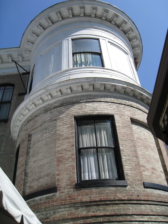 Close-up of the Lemp Mansion's bow-front brick turret and bracketed cornice.
