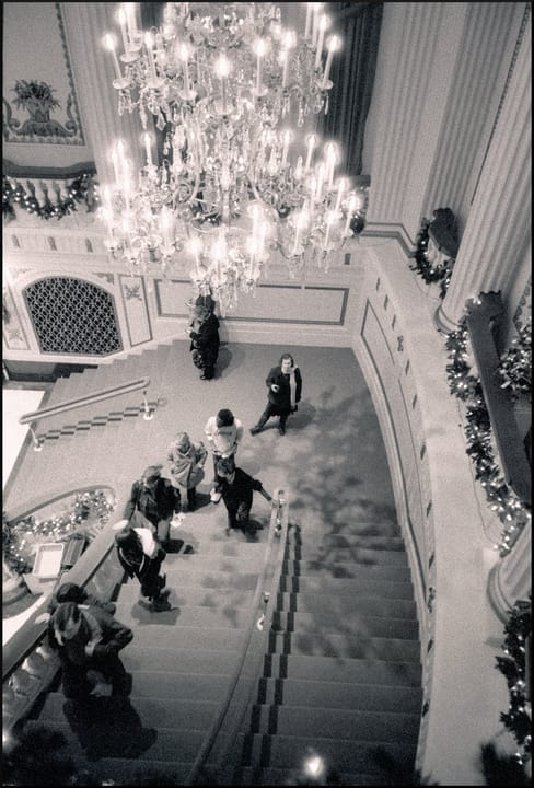 The grand staircase and crystal chandelier of Powell Hall's foyer, seen from above and decorated with holiday garland (black-and-white film photograph).