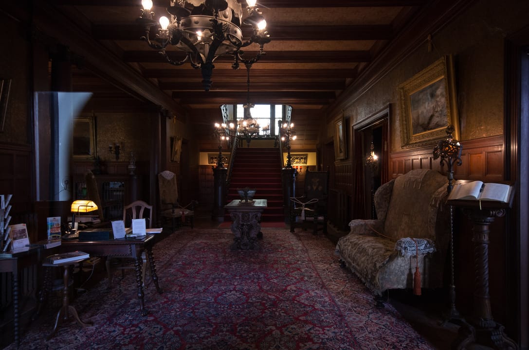 The mansion's grand entrance hallway, with its carved staircase, chandeliers and wood-paneled walls.