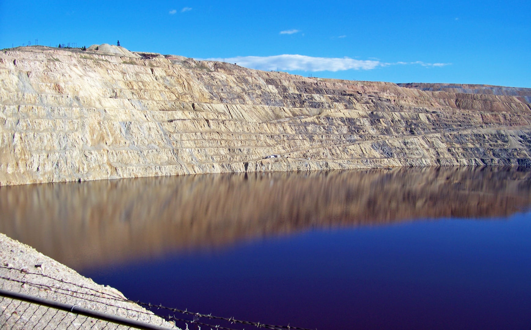 Aerial view of the Berkeley Pit toxic lake in Butte, Montana, showing the rust-orange and blue-green acidic water surrounded by terraced mine walls