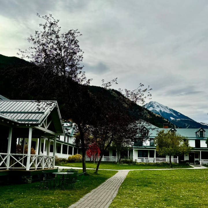 The lodge's porches and guest rooms along the lawn, with autumn trees and the Absaroka foothills behind, at Chico Hot Springs.