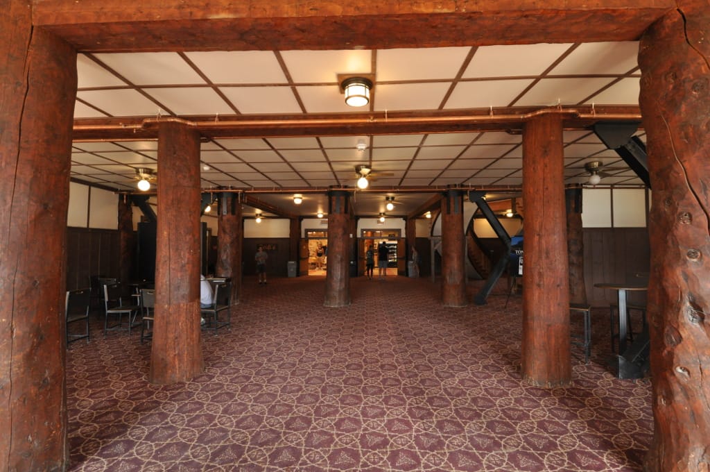A ground-floor corridor inside Many Glacier Hotel's downstairs lobby, lined with log posts, Glacier National Park, Montana.