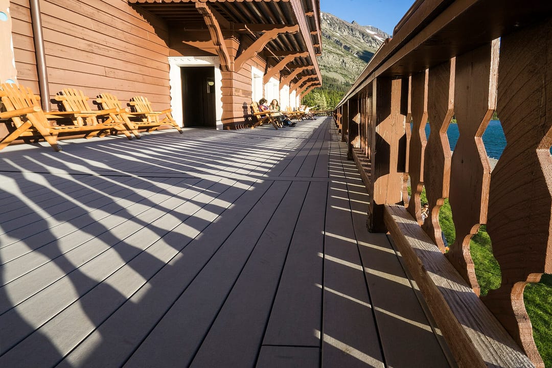 The lakeside log-post porch of Many Glacier Hotel, lined with Adirondack chairs, Glacier National Park, Montana.