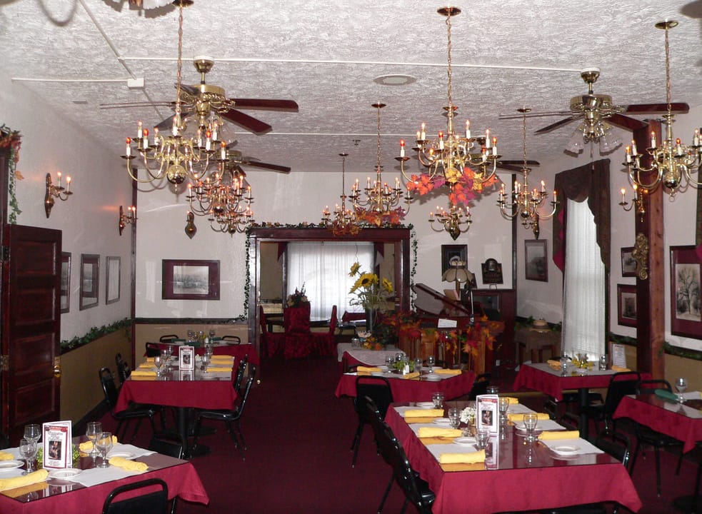 Dining room inside the Historic Argo Hotel, Crofton, Nebraska, set with linens under pressed-tin ceiling and chandeliers.