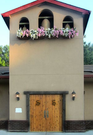 Monastery-inspired stucco entrance facade of Brother Sebastian's Steak House & Winery in Omaha, Nebraska, with wooden double doors marked with twin S monograms