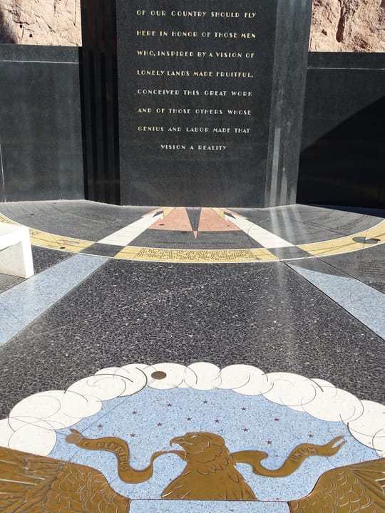The dedication inscription and star-map terrazzo floor at the Hoover Dam memorial plaza on the Nevada rim.