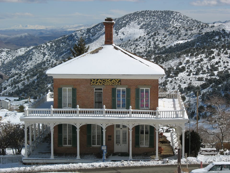The Mackay Mansion under snow with the Virginia Range mountains behind it, winter.