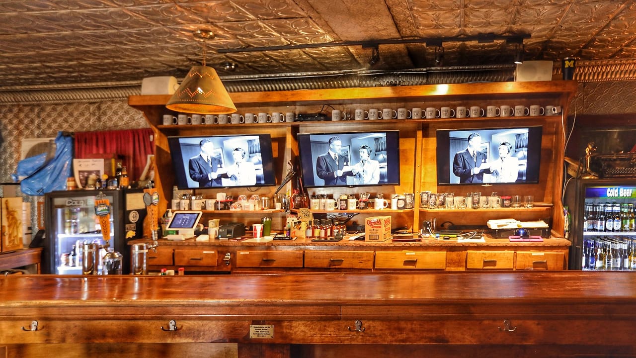 The Pioneer Saloon's back bar, with a plaque reading 'Manufactured for the Pioneer Saloon's 100th Anniversary ... 1913-2013' on the counter front, Goodsprings, Nevada.