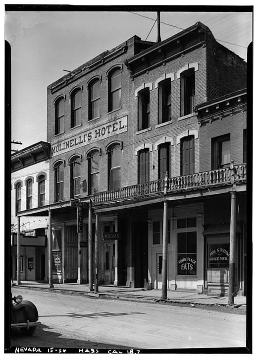 The brick building on C Street, Virginia City, with 'Molinelli's Hotel' painted across its upper floors (today the Silver Queen Hotel), photographed for the Historic American Buildings Survey in the 1930s; a hotel sign and a storefront with an 'Eats'