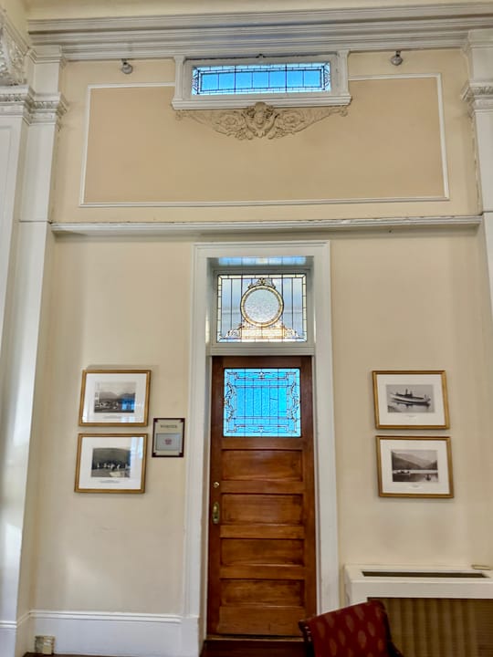 A stained-glass transom and doorway flanked by historic photographs in the hotel's lobby, Bretton Woods, NH.