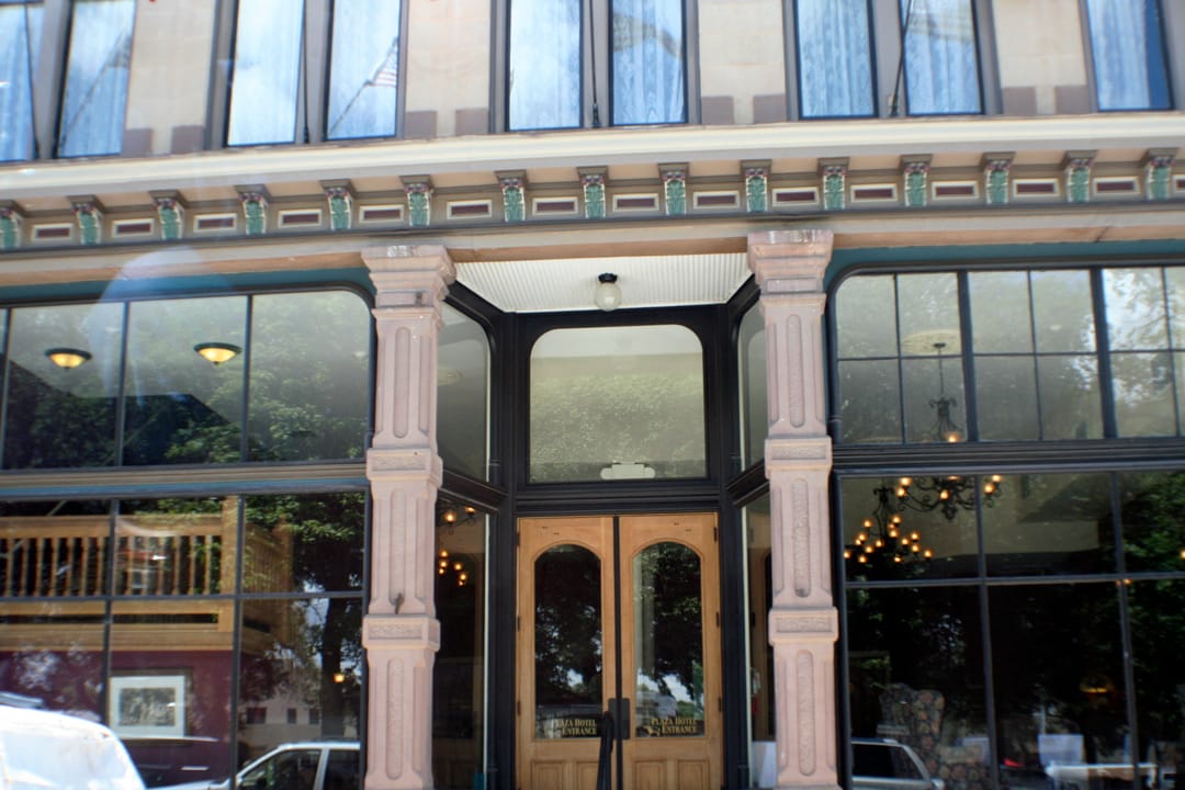 The Plaza Hotel's glass-and-wood entrance, with PLAZA HOTEL ENTRANCE lettered on the doors, Las Vegas, New Mexico.