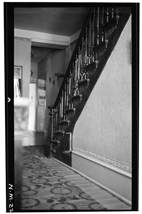 Historic American Buildings Survey interior photograph (frame 7-2 of set HABS NM-115, documentation compiled after 1933): the staircase and hall at the St. James Hotel, Cimarron, New Mexico, with a turned-baluster stair, scrolled step brackets and a 