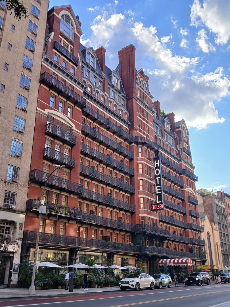 The red-brick Victorian Gothic and Queen Anne Revival exterior of the Hotel Chelsea seen from across West 23rd Street in Manhattan
