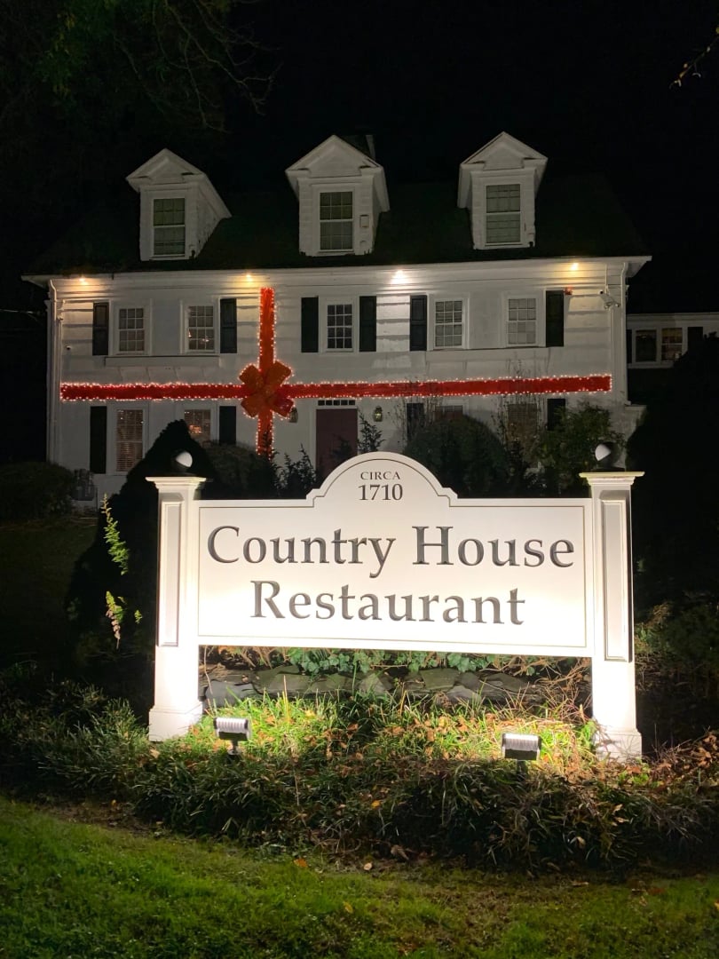 Exterior of the 1710 Country House Restaurant colonial building in Stony Brook, New York, with a holiday red bow on the door