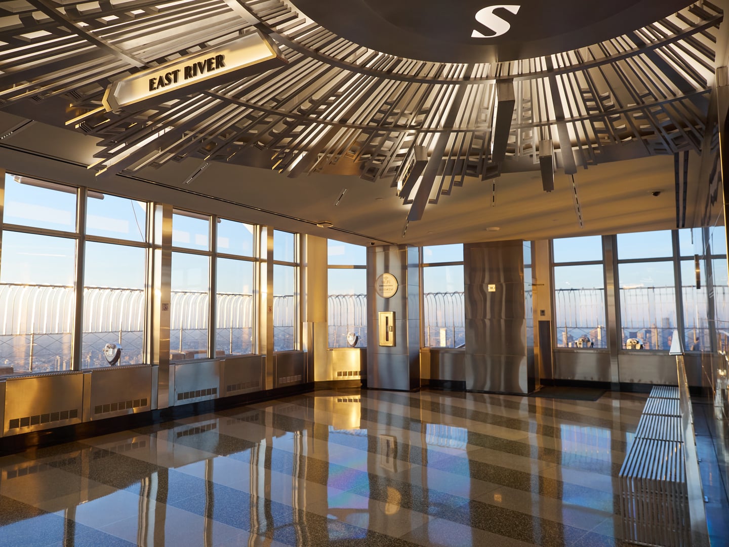 Open-air 86th floor observation deck of the Empire State Building in Midtown Manhattan, with the city skyline visible beyond the safety barriers.